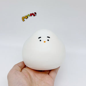 Hand holding white chonky bird slow-rising squishy toy, front face view, size reference
