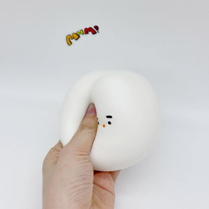Hand squeezing white chonky bird squishy toy, slow-rise foam deforming under finger pressure