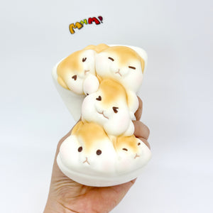 Hand holding 3D hamster toast slow rise squishy front view, golden brown kawaii stress toy