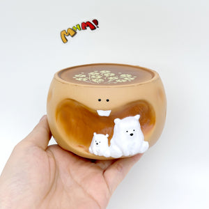 Hand holding caramel coffee cup squeeze toy with white polar bear figurines and floral latte art