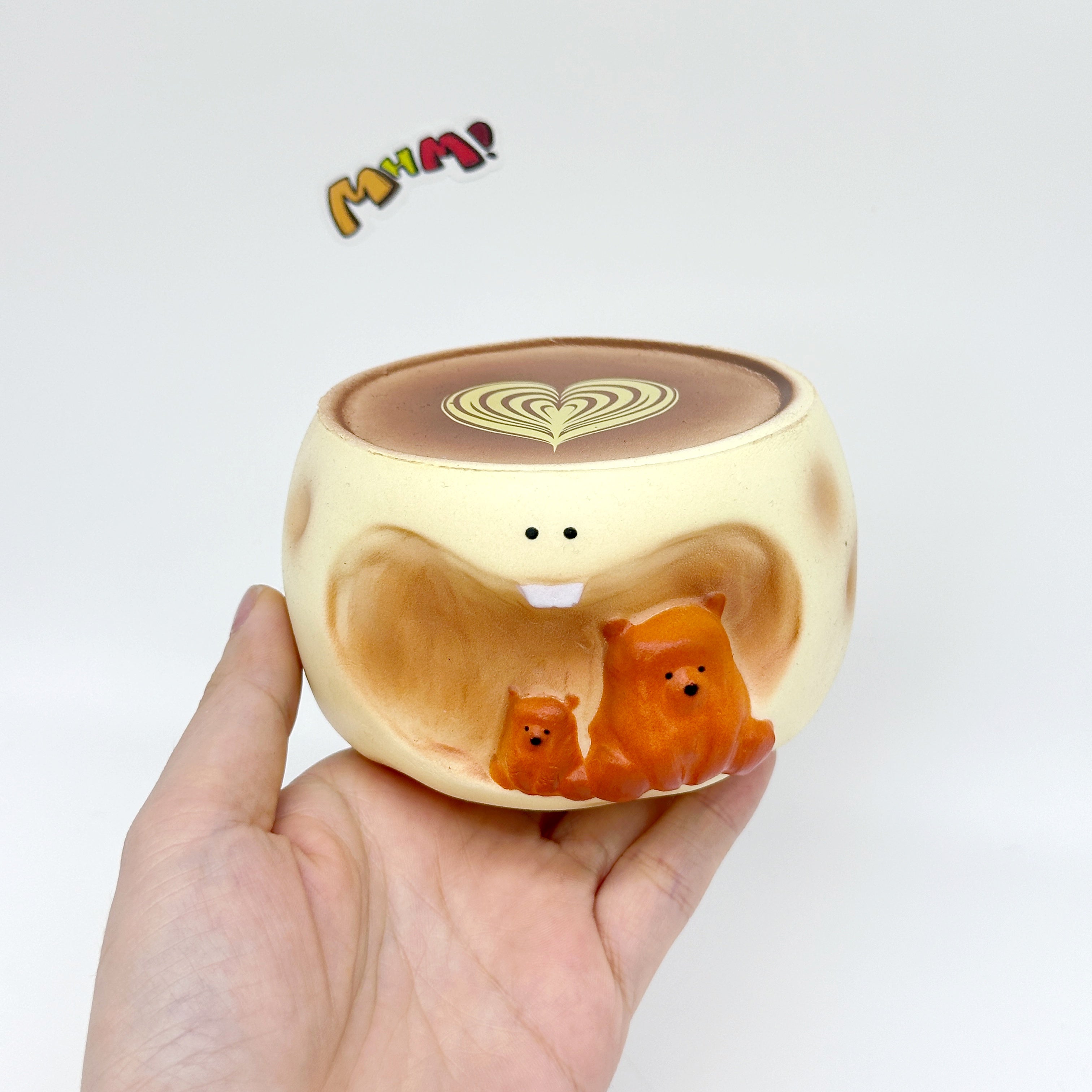 Hand holding bear coffee cup squishy toy with heart latte art and orange bears