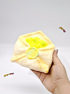 Hand squeezing soft green envelope stress toy showing slow rising foam material