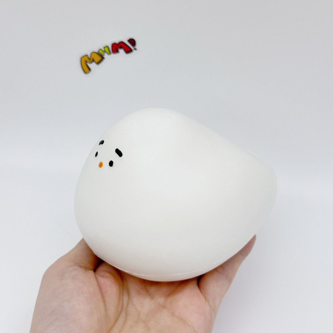 Hand holding white chubby bird squishy toy tilted angle, showing squeezable soft texture