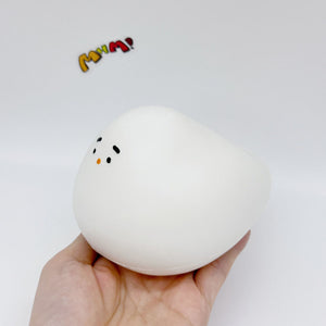 Hand holding white chubby bird squishy toy tilted angle, showing squeezable soft texture