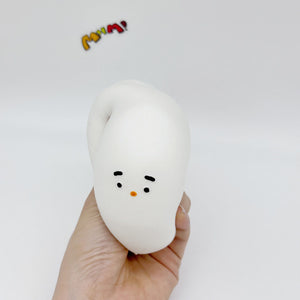 Hand holding squeezed white bird squishy with distorted funny face, orange beak detail visible