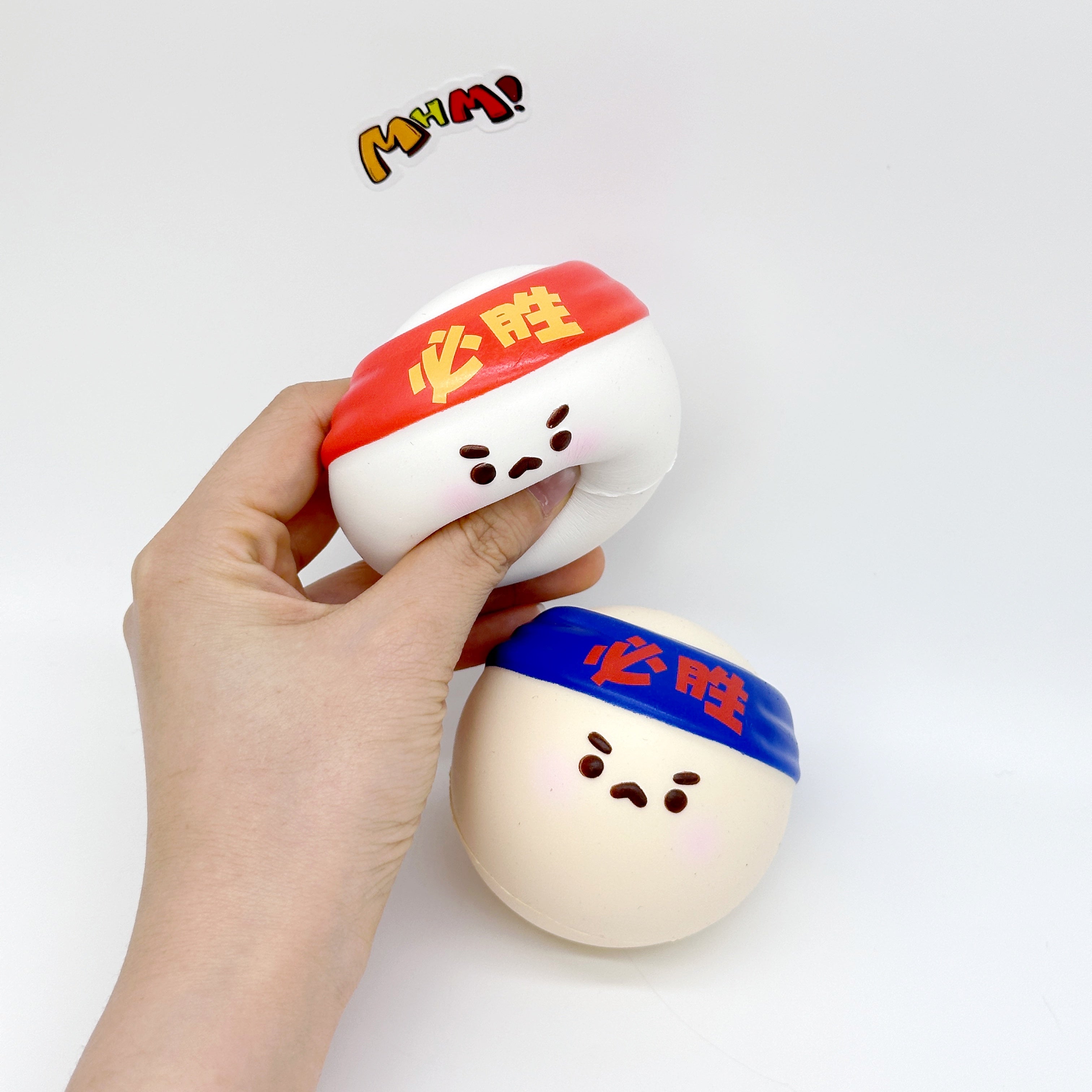 Hand squeezing red headband table tennis squishy toy beside blue version on white background