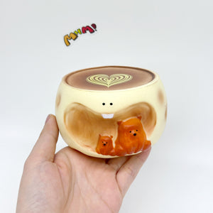 Hand holding bear coffee cup squishy toy with heart latte art and orange bears
