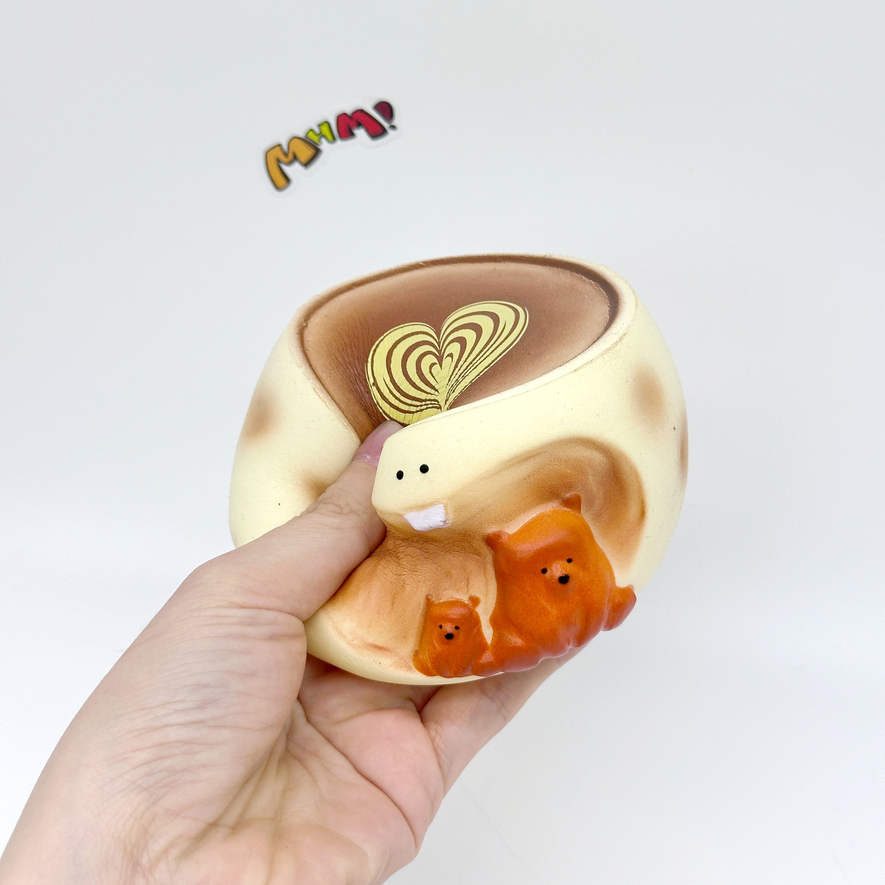 Hand holding bear coffee cup squeeze toy with latte art heart and orange bear figures