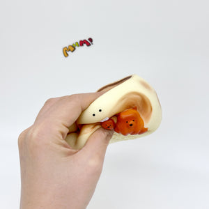 Hand squeezing deformed cream coffee cup stress toy revealing orange bears inside