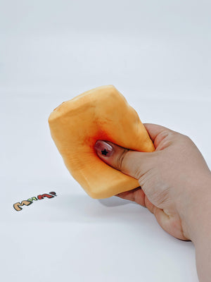 Hand squeezing sticky yellow rice cake stress toy showing slow rising moist foam