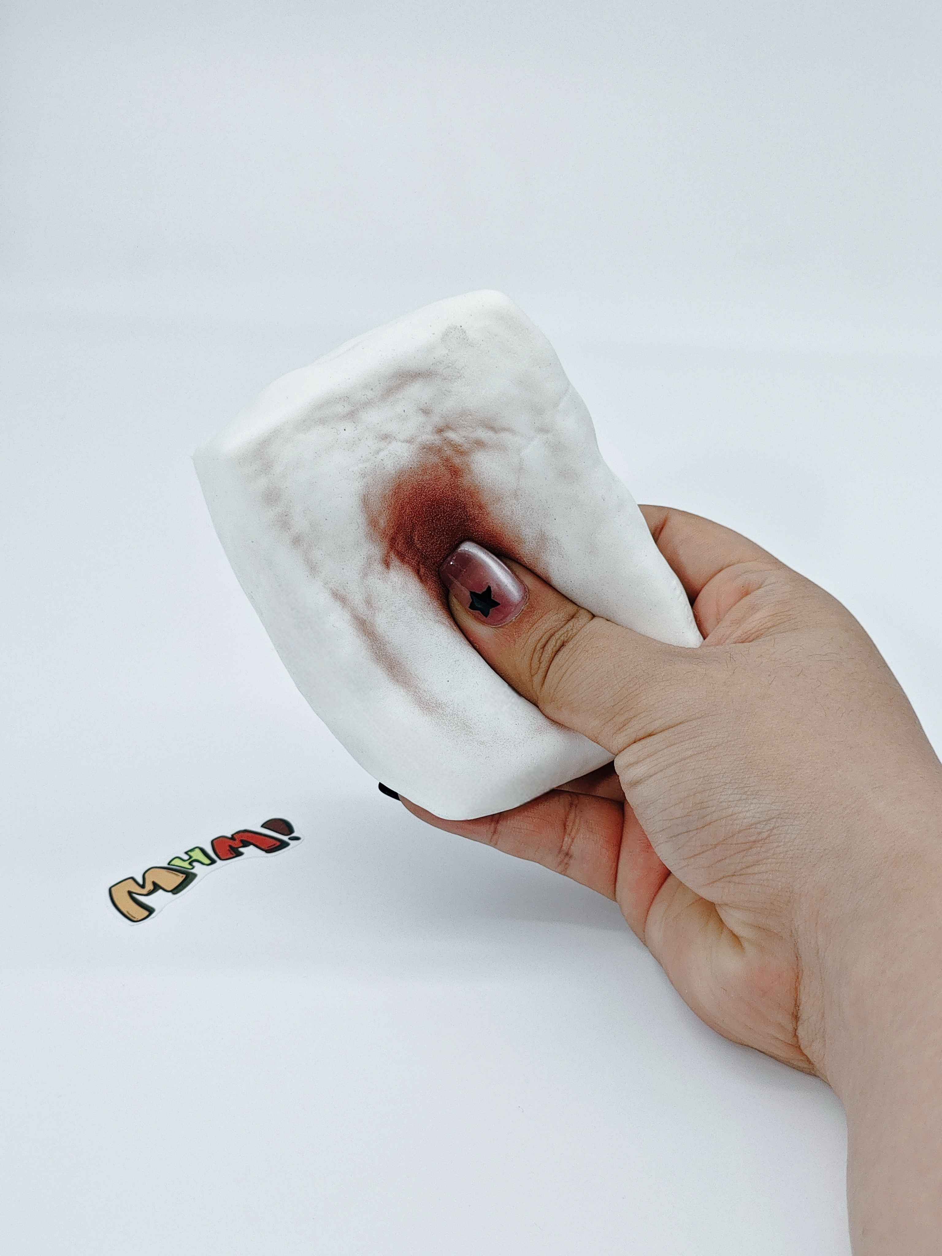 Hand squeezing sticky roasted mochi stress toy showing slow rising dough like foam