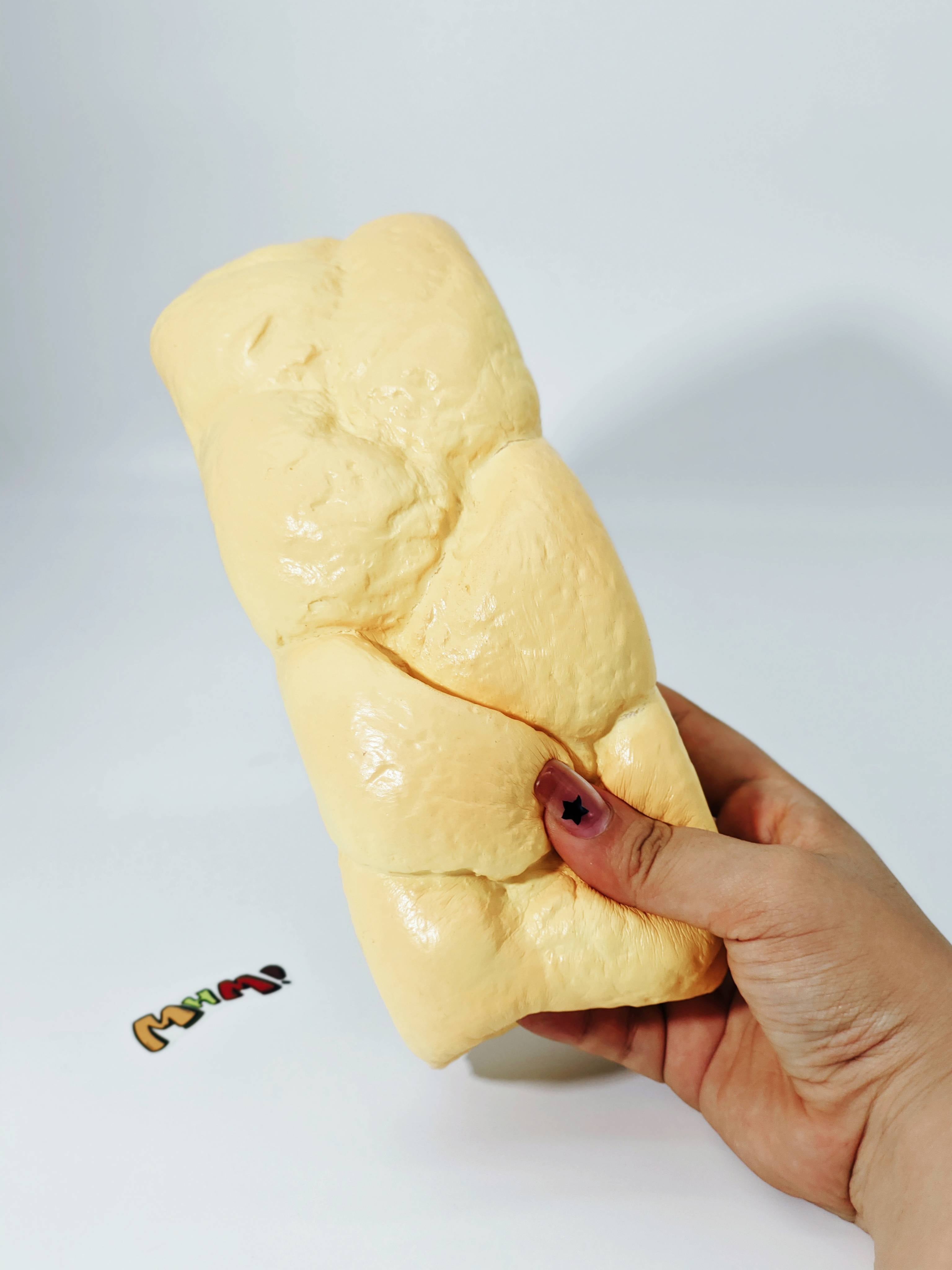Hand squeezing big braided dough stress toy showing slow rising foam and floral scent