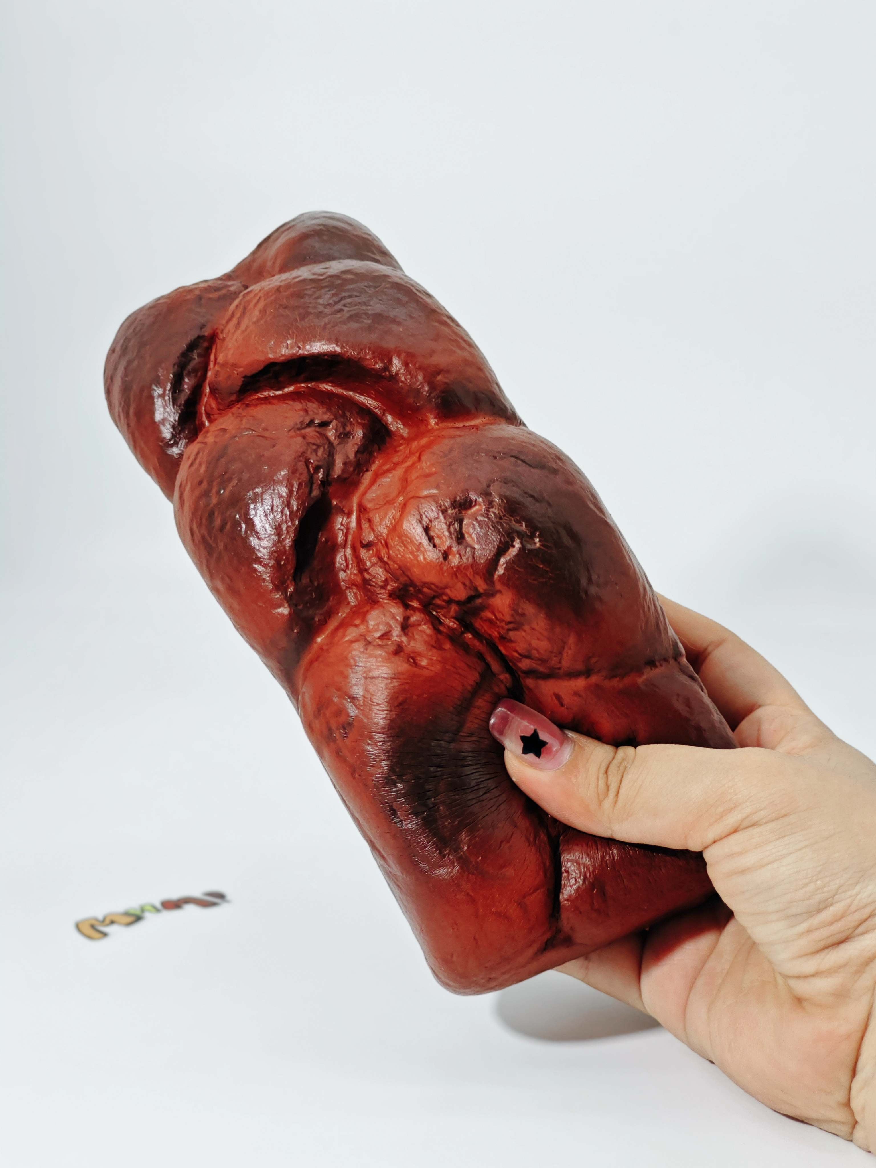 Hand squeezing cookie scented braided bread stress toy showing moist foam rebound