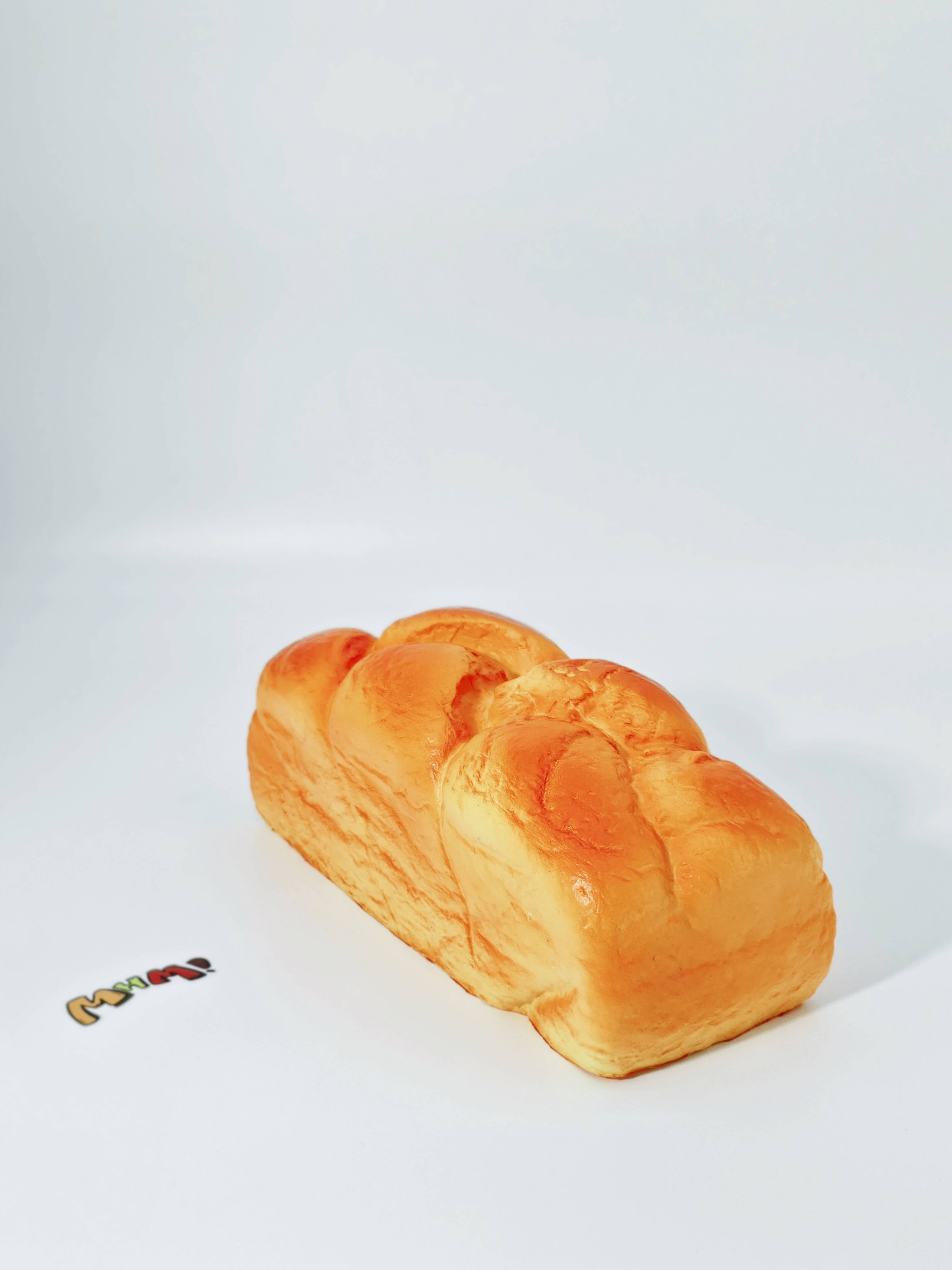 Hand squeezing fresh baked bread scented stress toy showing moist foam rebound for anxiety