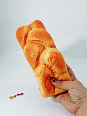 Hand squeezing fresh baked bread scented stress toy showing moist foam rebound for anxiety